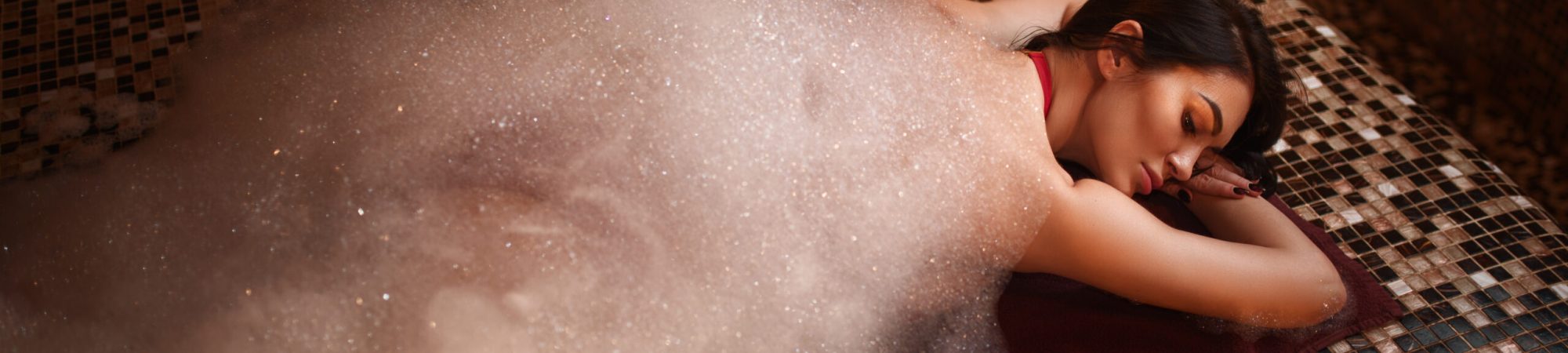 Woman in foam lying on a hot stone, turkish bath, hamam, sauna, top view. Skin and body care