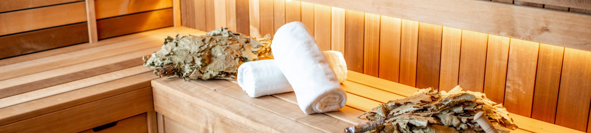 Bath brooms with towels on the bench at the russian traditional sauna